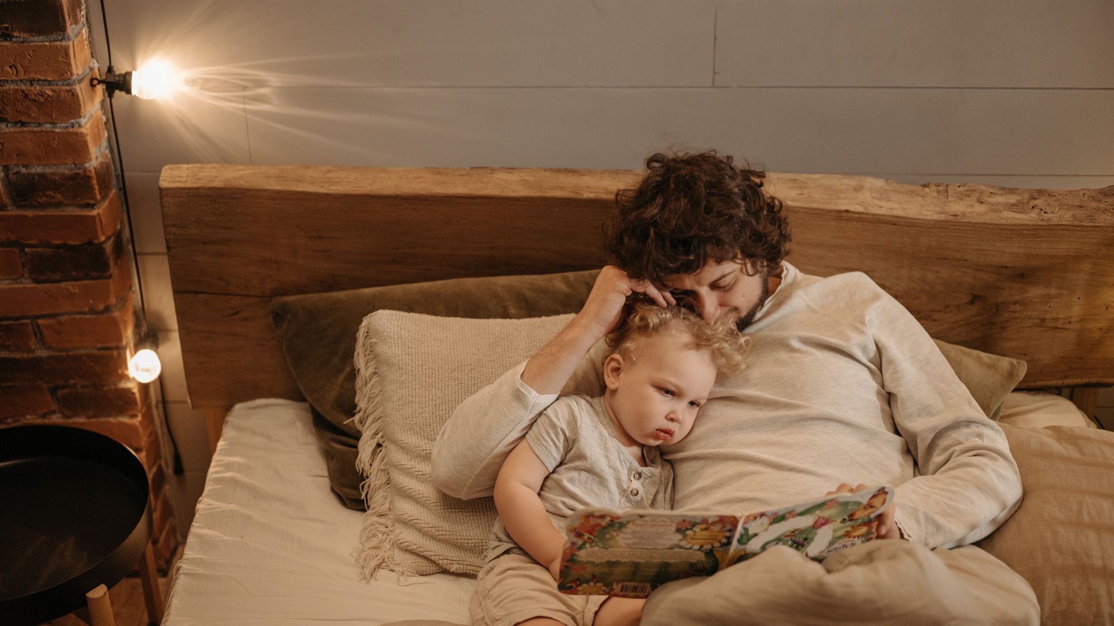 Parent et son enfant lisant un livre au lit.